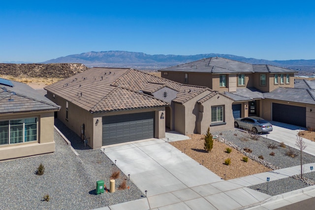 view of front facade with an attached garage, a mountain view, stucco siding, and concrete driveway