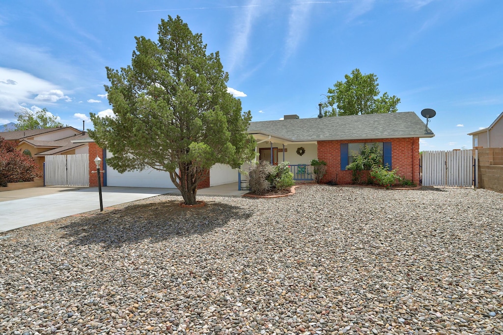 view of front of property featuring brick siding, driveway, fence, and a gate