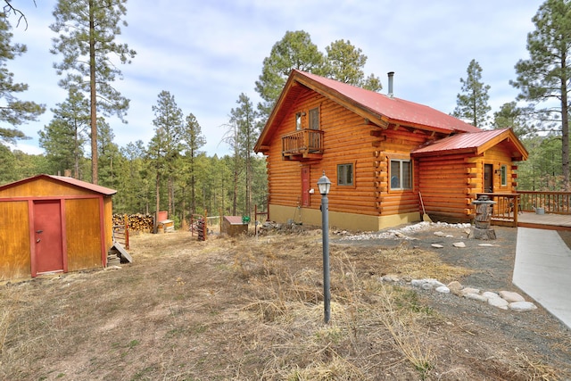 view of home's exterior with a storage unit, log siding, a wooden deck, an outdoor structure, and metal roof