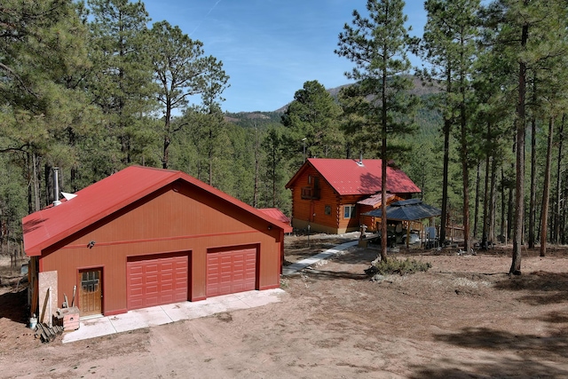 garage with driveway and a wooded view