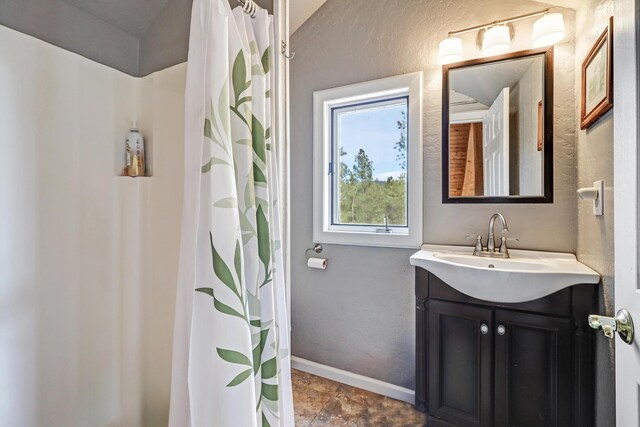 bathroom with a shower with shower curtain, a textured wall, baseboards, and vanity
