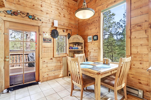 dining space with plenty of natural light, wood walls, light tile patterned floors, and baseboard heating
