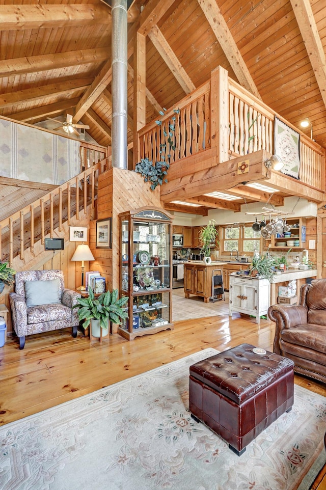 living area with high vaulted ceiling, wood ceiling, light wood finished floors, and beam ceiling