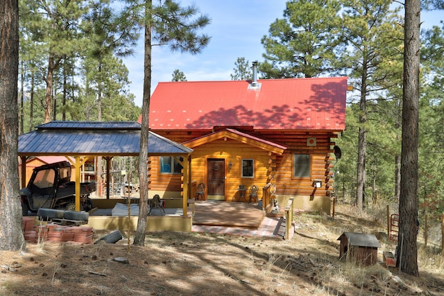 rear view of property with log exterior and metal roof