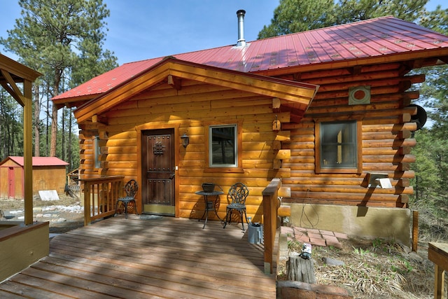 exterior space with a deck, an outbuilding, log exterior, and a storage unit