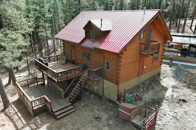 back of house with a deck, stairs, log exterior, metal roof, and a forest view