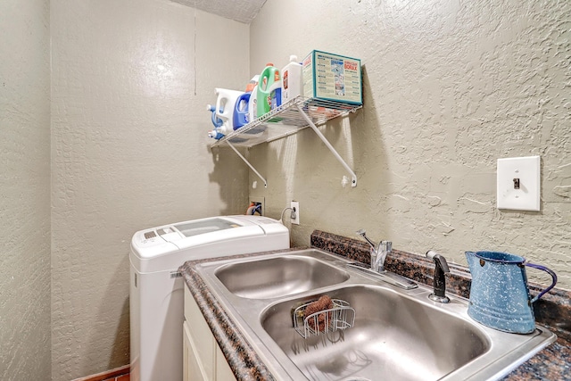 laundry room with laundry area, a sink, a textured wall, and washer and clothes dryer