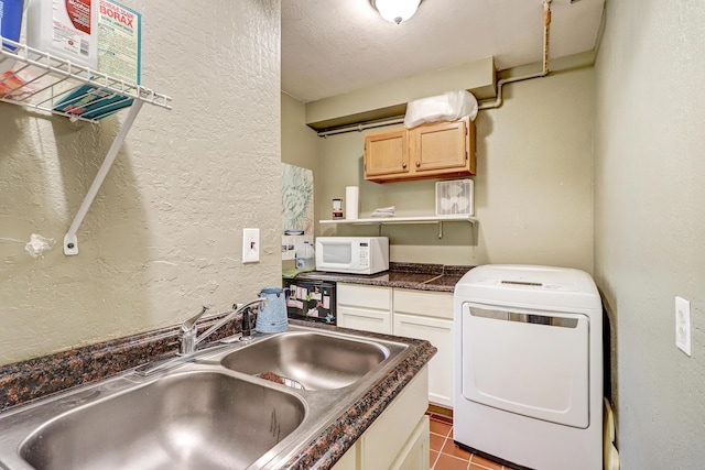 laundry room with cabinet space, a textured wall, a sink, tile patterned floors, and washer / dryer