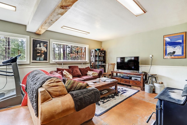 living area with concrete floors, wainscoting, and beamed ceiling