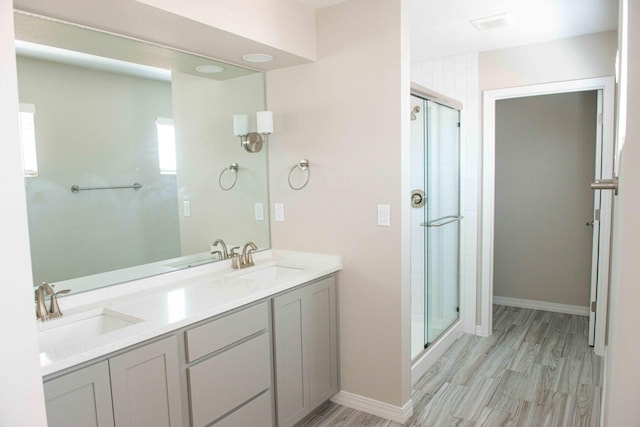 full bath with wood finished floors, double vanity, a sink, and a stall shower