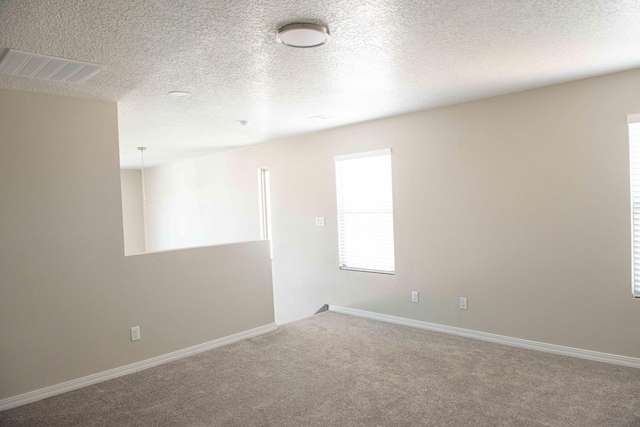 empty room featuring baseboards, a textured ceiling, carpet, and visible vents
