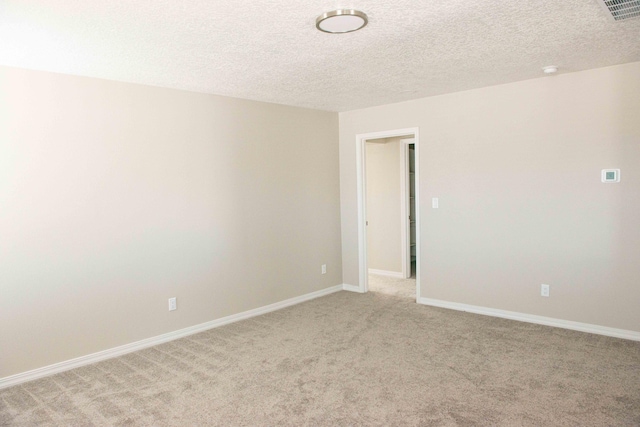 empty room with baseboards, light colored carpet, a textured ceiling, and visible vents