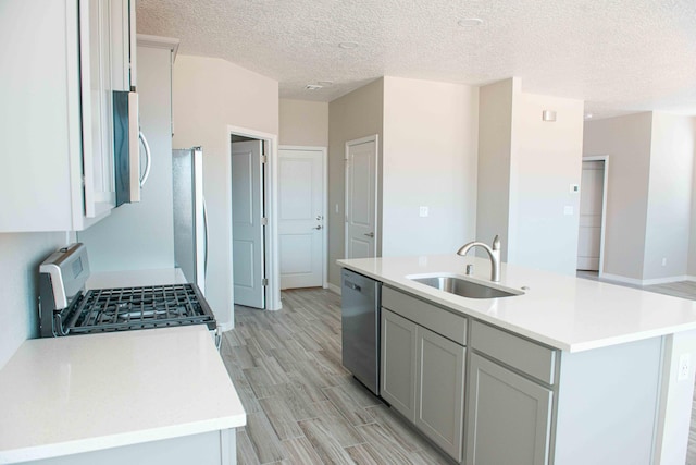 kitchen featuring light countertops, a sink, a textured ceiling, and stainless steel appliances