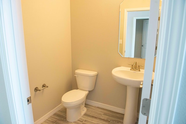 bathroom with baseboards, toilet, and wood finished floors