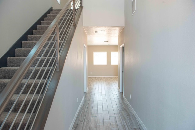 interior space featuring baseboards, visible vents, wood finished floors, and stairway