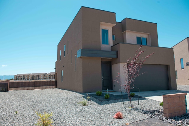 view of front of property featuring a garage, fence, stucco siding, and concrete driveway