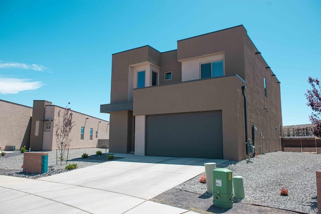 modern home with fence, an attached garage, driveway, and stucco siding