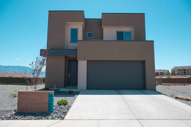 contemporary home with stucco siding, fence, and driveway