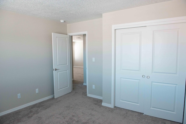 unfurnished bedroom with baseboards, carpet, a closet, and a textured ceiling