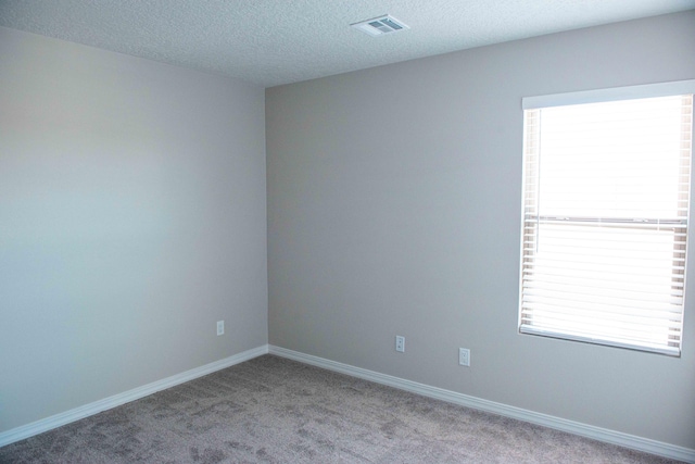 carpeted spare room featuring a textured ceiling, baseboards, and visible vents