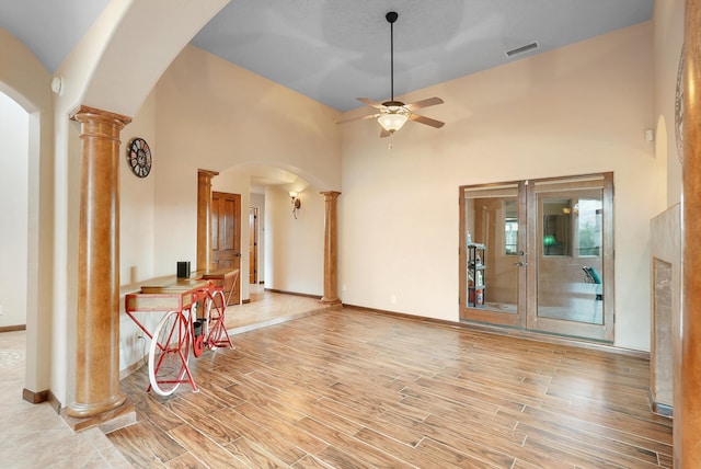 3101 Rachel Ct NE, Rio Rancho, NM 87144 - unfurnished living room with ornate columns, light wood-style floors, a ceiling fan, arched walkways, and a high ceiling