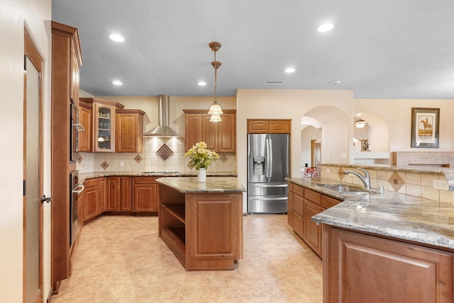 3101 Rachel Ct NE, Rio Rancho, NM 87144 - kitchen with stainless steel appliances, a sink, wall chimney range hood, brown cabinets, and arched walkways