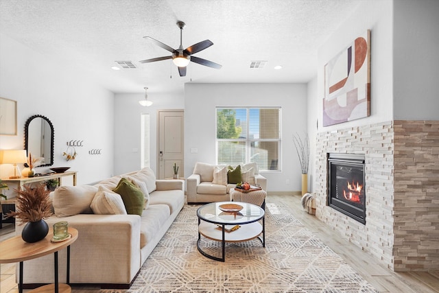 living area with light wood-style floors, a ceiling fan, a textured ceiling, and visible vents