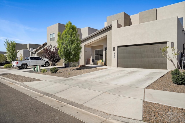 contemporary house with an attached garage, driveway, and stucco siding