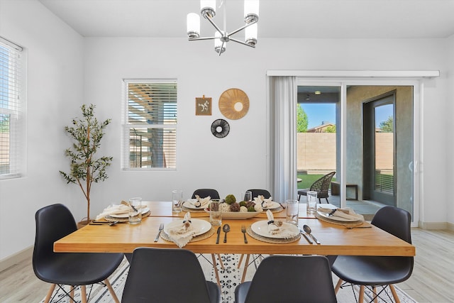 dining room with baseboards, an inviting chandelier, and light wood-style floors