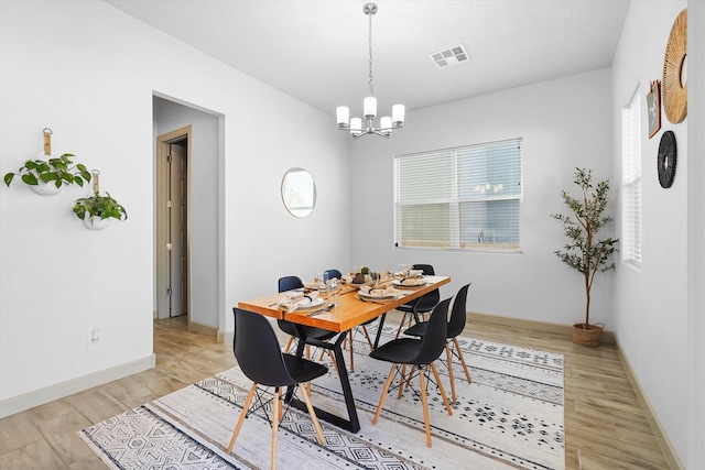 dining area with visible vents, light wood-style floors, baseboards, and an inviting chandelier
