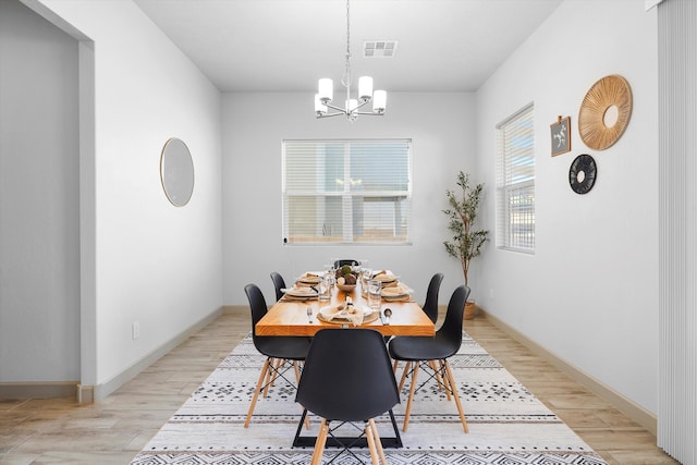 dining space featuring baseboards, a chandelier, visible vents, and light wood-style floors