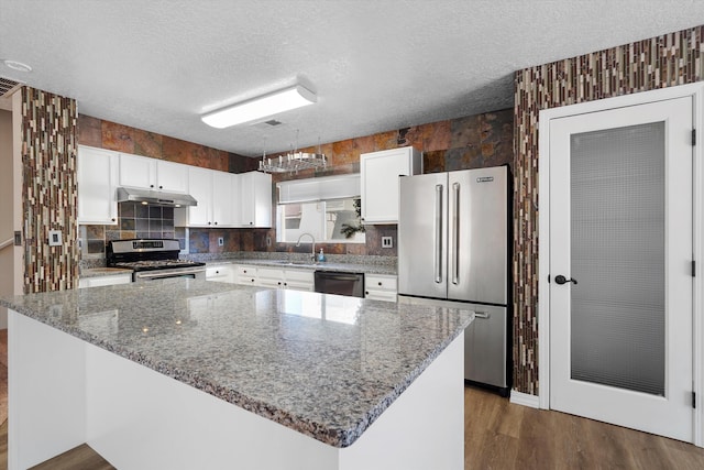 7700 Briar Ridge Ave NW, Albuquerque, NM 87114 - kitchen with white cabinets, appliances with stainless steel finishes, stone countertops, dark wood-type flooring, and under cabinet range hood