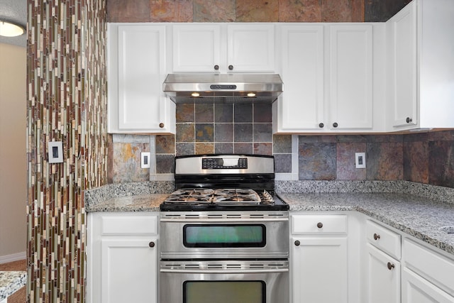 7700 Briar Ridge Ave NW, Albuquerque, NM 87114 - kitchen featuring light stone countertops, range with two ovens, baseboards, tasteful backsplash, and under cabinet range hood