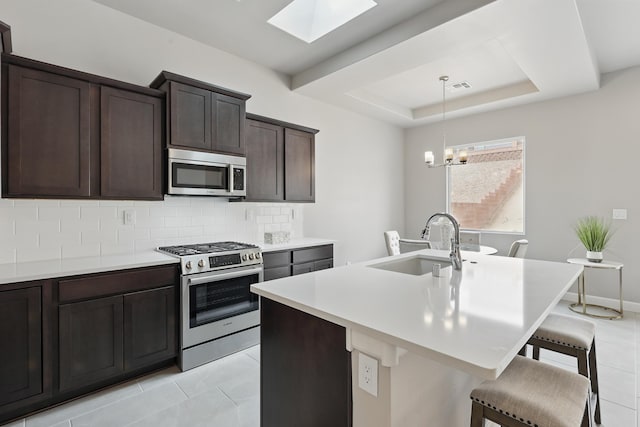 1718 Tesoro Loop NW, Los Lunas, NM 87031 - kitchen with stainless steel appliances, a sink, backsplash, a kitchen bar, and a skylight