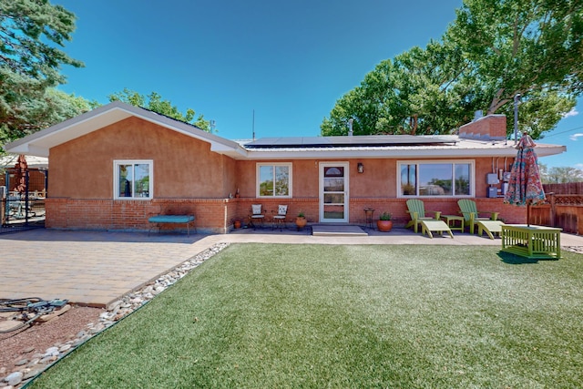 5 Hobbs Rd, Peralta, NM 87042 - rear view of house with brick siding, roof mounted solar panels, stucco siding, and a chimney