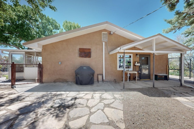 back of house with fence, a gate, a patio, and stucco siding