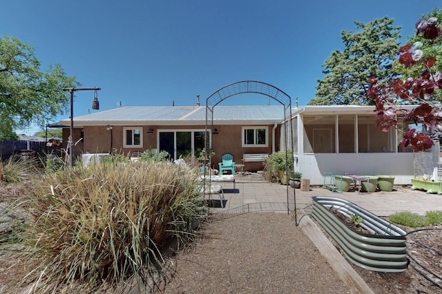 back of property with a sunroom and a patio area