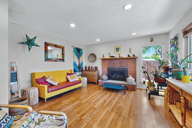 living area with recessed lighting, a textured ceiling, light wood finished floors, and a fireplace