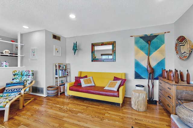 living area featuring recessed lighting, a textured ceiling, visible vents, and wood finished floors