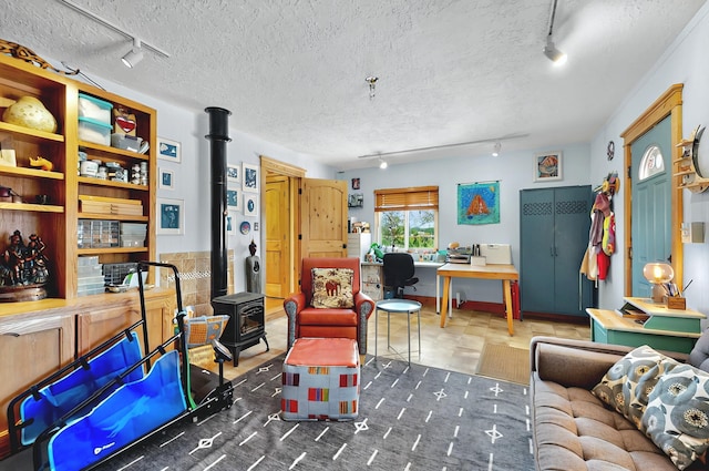 living area featuring track lighting, a wood stove, and a textured ceiling