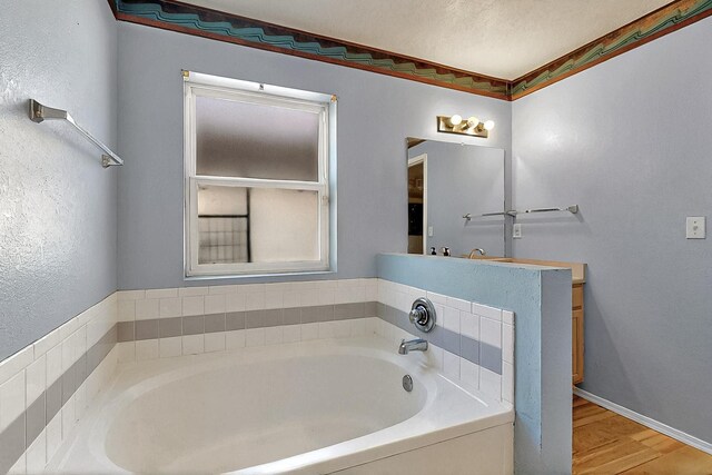 5401 Crown Ridge Rd NW, Albuquerque, NM 87114 - bathroom featuring a garden tub, wood finished floors, a textured wall, vanity, and baseboards