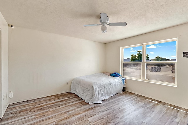 5401 Crown Ridge Rd NW, Albuquerque, NM 87114 - bedroom featuring wood finished floors, a textured ceiling, a ceiling fan, and baseboards