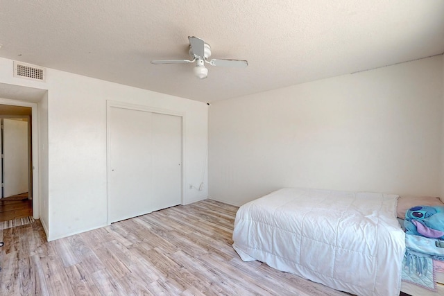 5401 Crown Ridge Rd NW, Albuquerque, NM 87114 - bedroom with light wood-type flooring, ceiling fan, a closet, and a textured ceiling