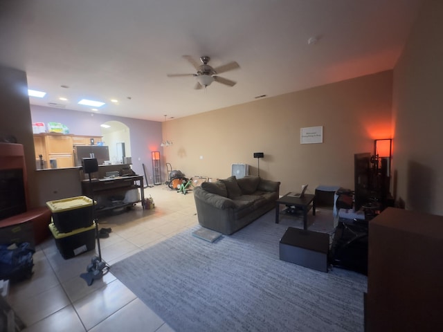 tiled living room featuring arched walkways and a ceiling fan