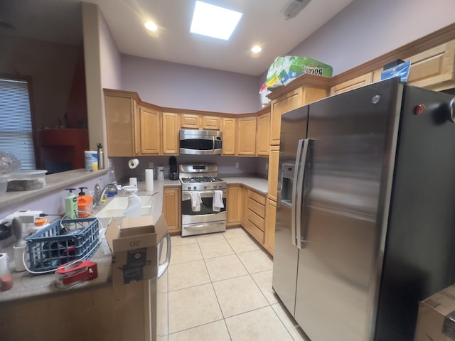kitchen with light brown cabinets, light countertops, a sink, appliances with stainless steel finishes, and light tile patterned floors