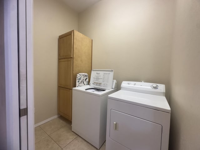 washroom featuring separate washer and dryer, baseboards, cabinet space, and light tile patterned floors