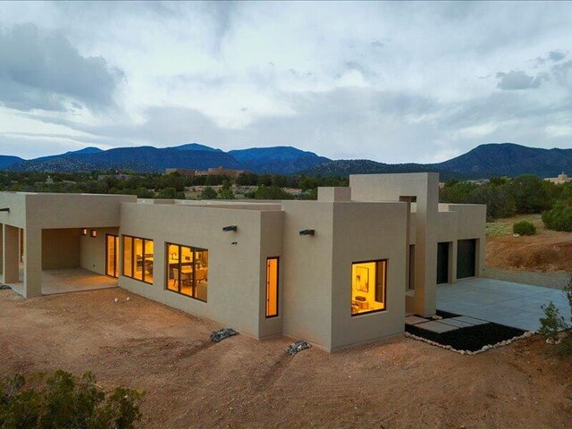 19 Anasazi Trl, Sandia Park, NM 87047 - back of property featuring a garage, a mountain view, stucco siding, and driveway