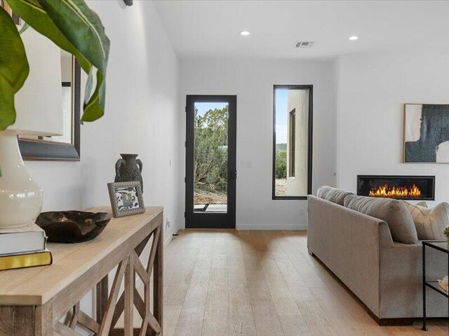 19 Anasazi Trl, Sandia Park, NM 87047 - living room with visible vents, light wood-type flooring, baseboards, a warm lit fireplace, and recessed lighting