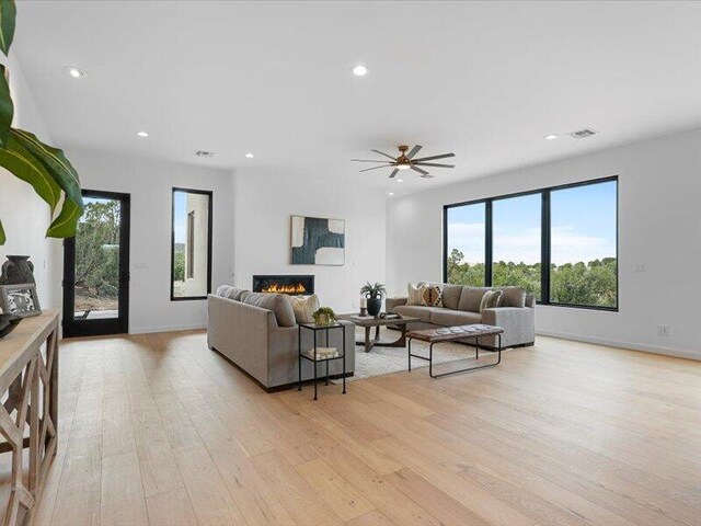 19 Anasazi Trl, Sandia Park, NM 87047 - living room featuring visible vents, recessed lighting, light wood-style flooring, and a warm lit fireplace