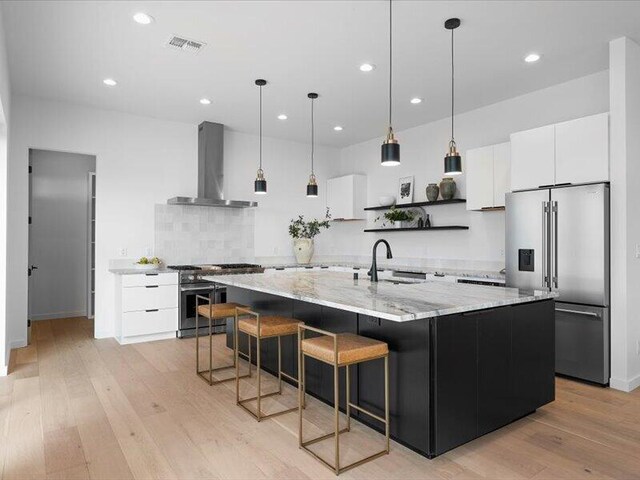 19 Anasazi Trl, Sandia Park, NM 87047 - kitchen featuring open shelves, high end appliances, wall chimney range hood, light wood-type flooring, and a sink